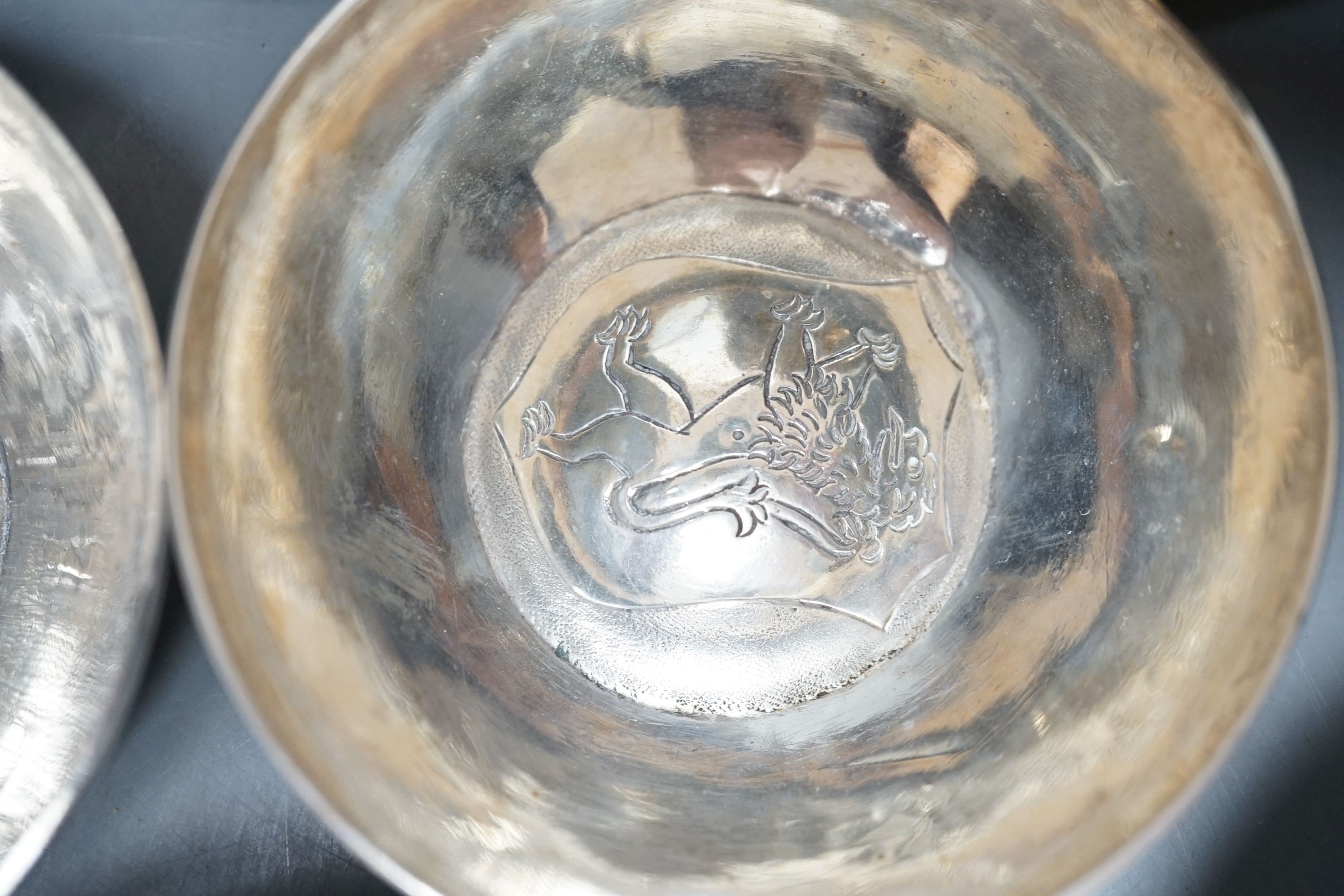 Four small Rangoon white metal bowls together with a simile basket and six small white metal bowls with heraldic motifs, gross 24.5oz.